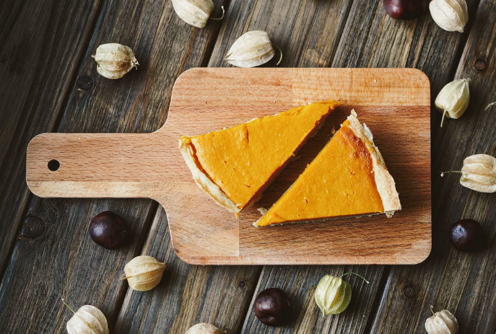 two slices of pumpkin pie on bamboo cutting board