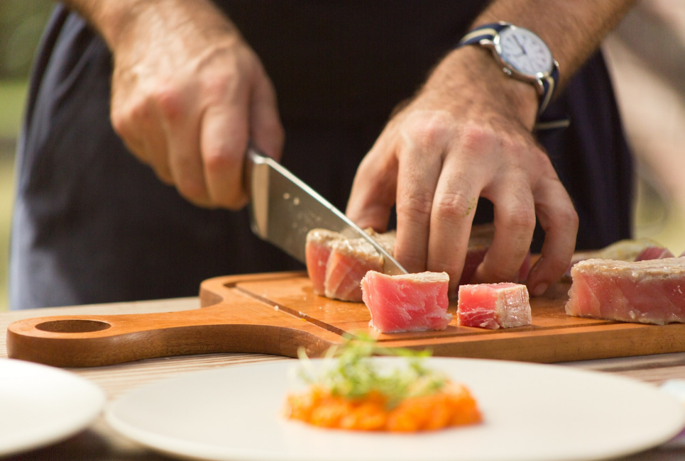 person cutting food on wooden cutting board
