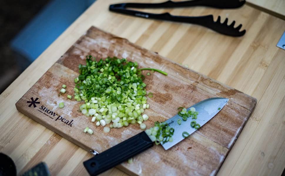 cutting board with chopped greens and a knife on top