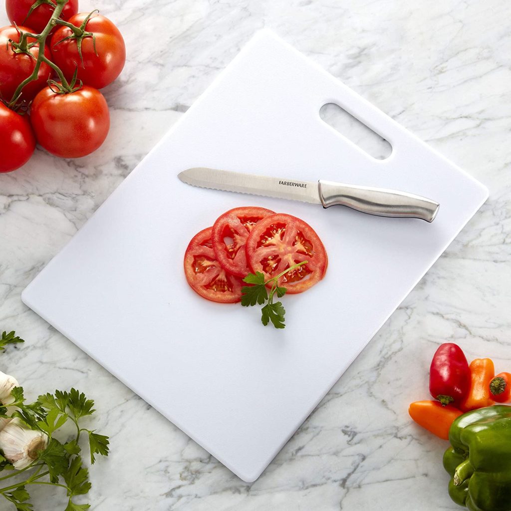 white cutting board with knife and thin sliced tomato on top