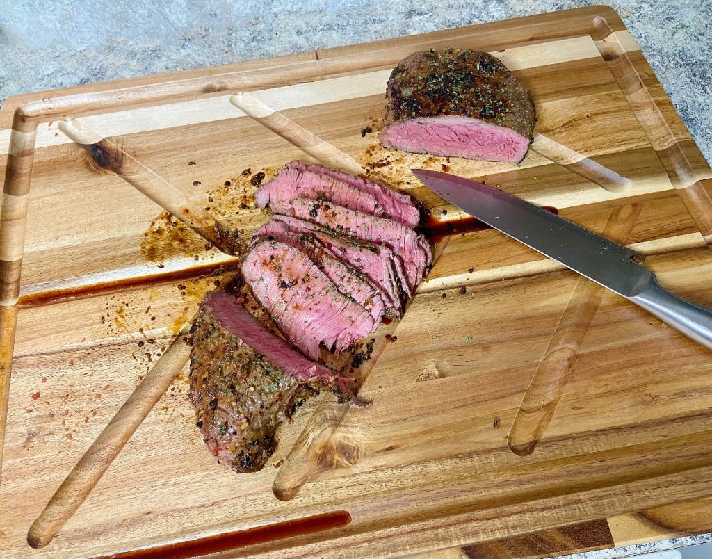 cutting board with cooked steak and a knife on top