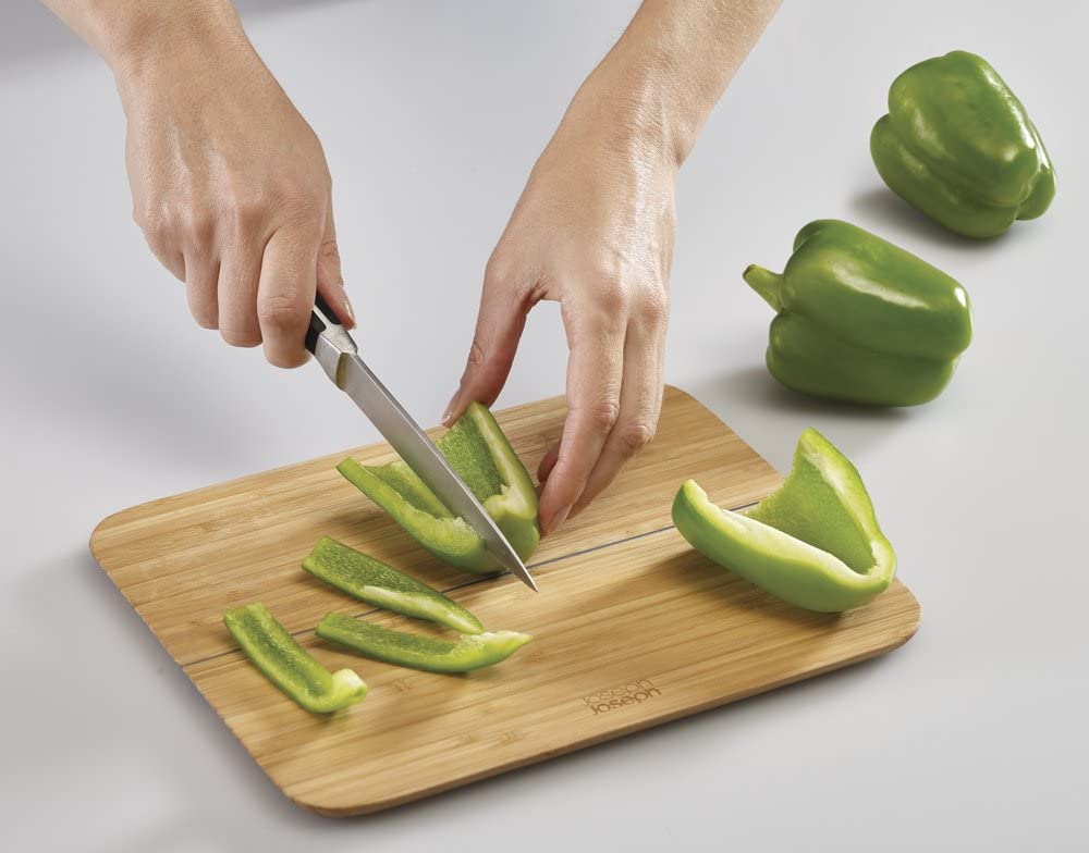 cutting board with peppers being chopped by human hands