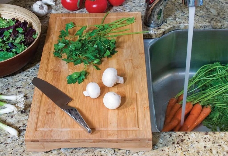 cutting over sink with vegetables on board and in sink