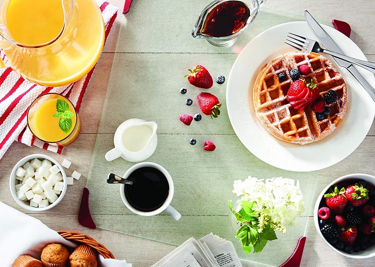 table filled with breakfast foods including waffles and fruit