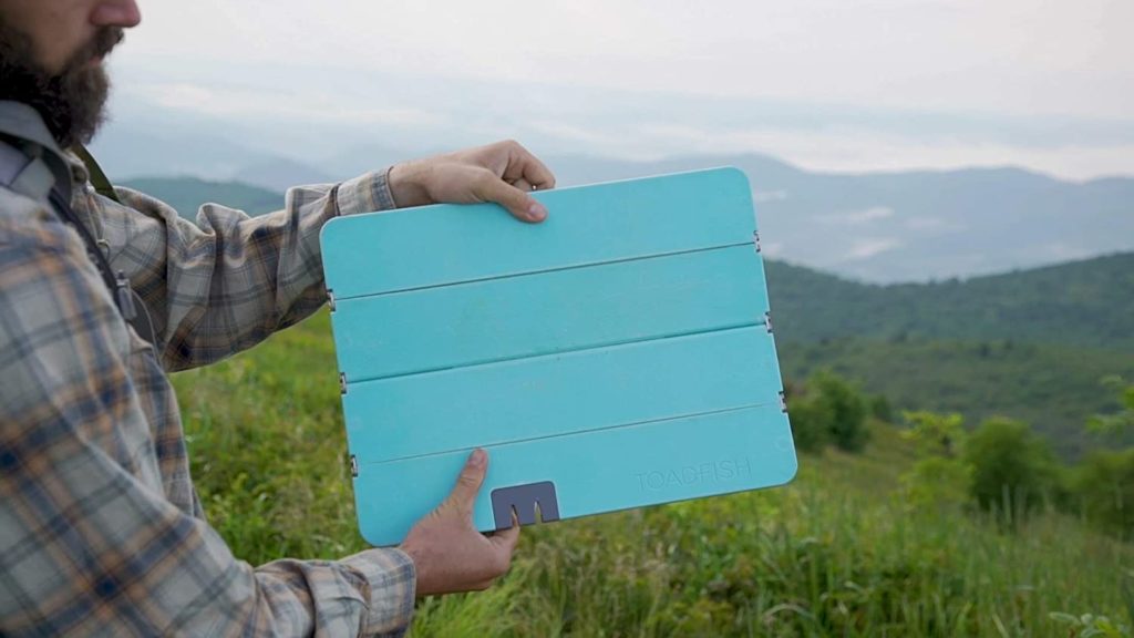 toadfish foldable cutting board blue in color being held by man on a hike