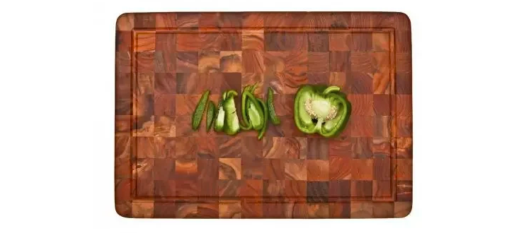 teak cutting board with sliced green pepper on it