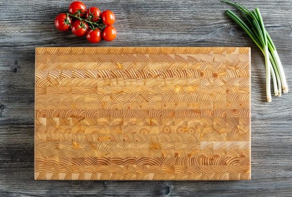 cutting board on kitchen table with tomatoes and scallion beside it