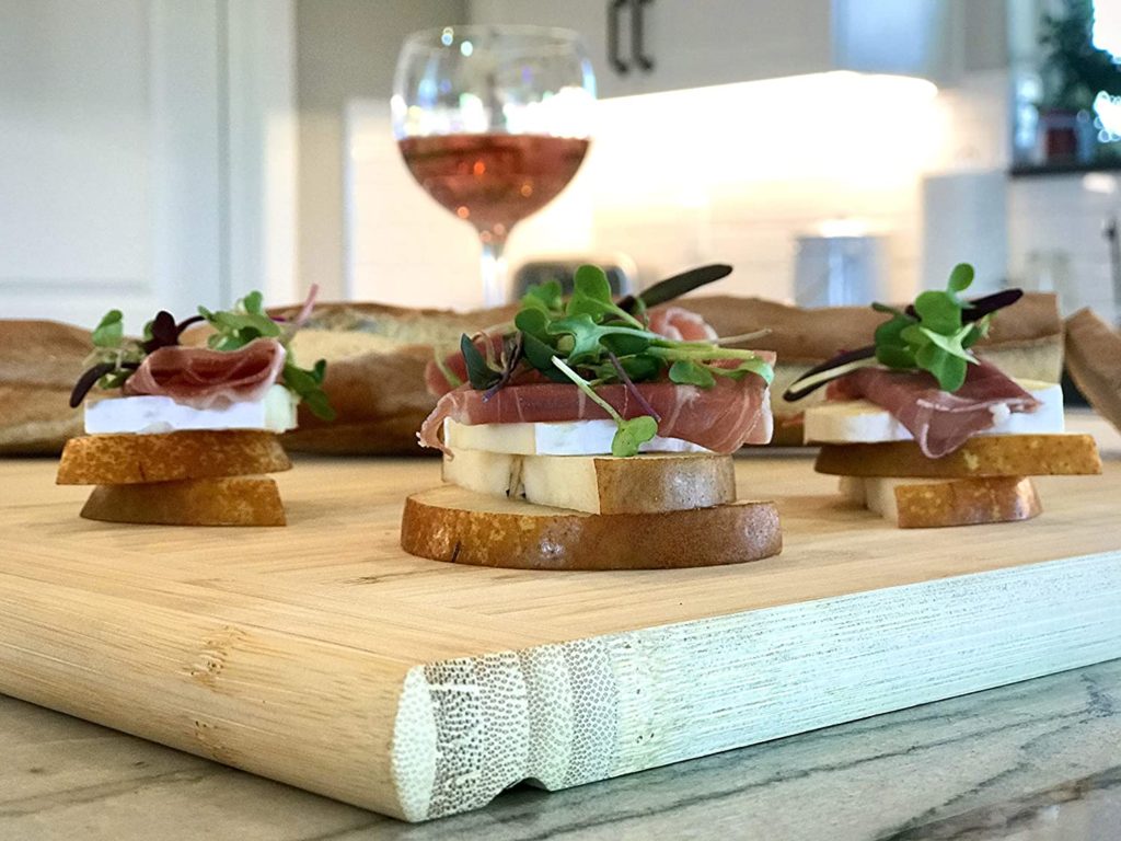 cutting board with pear and proscuitto appetizers on it