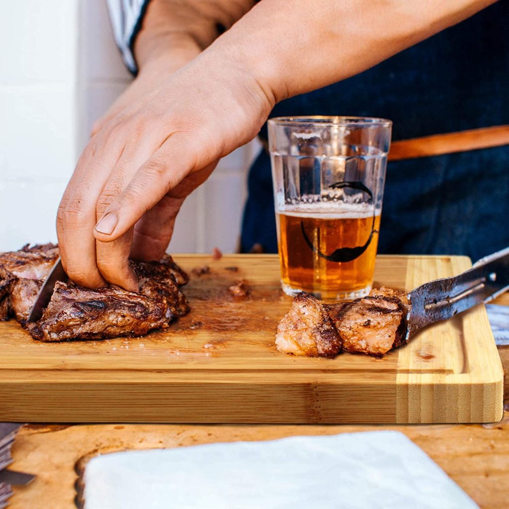 man using pull out cutting board with meat and beverage on top