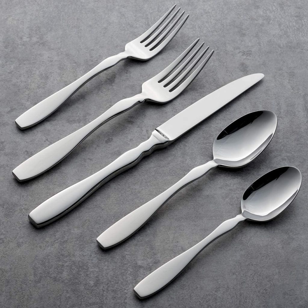 two silver forks, two spoons and one knife on grey stone