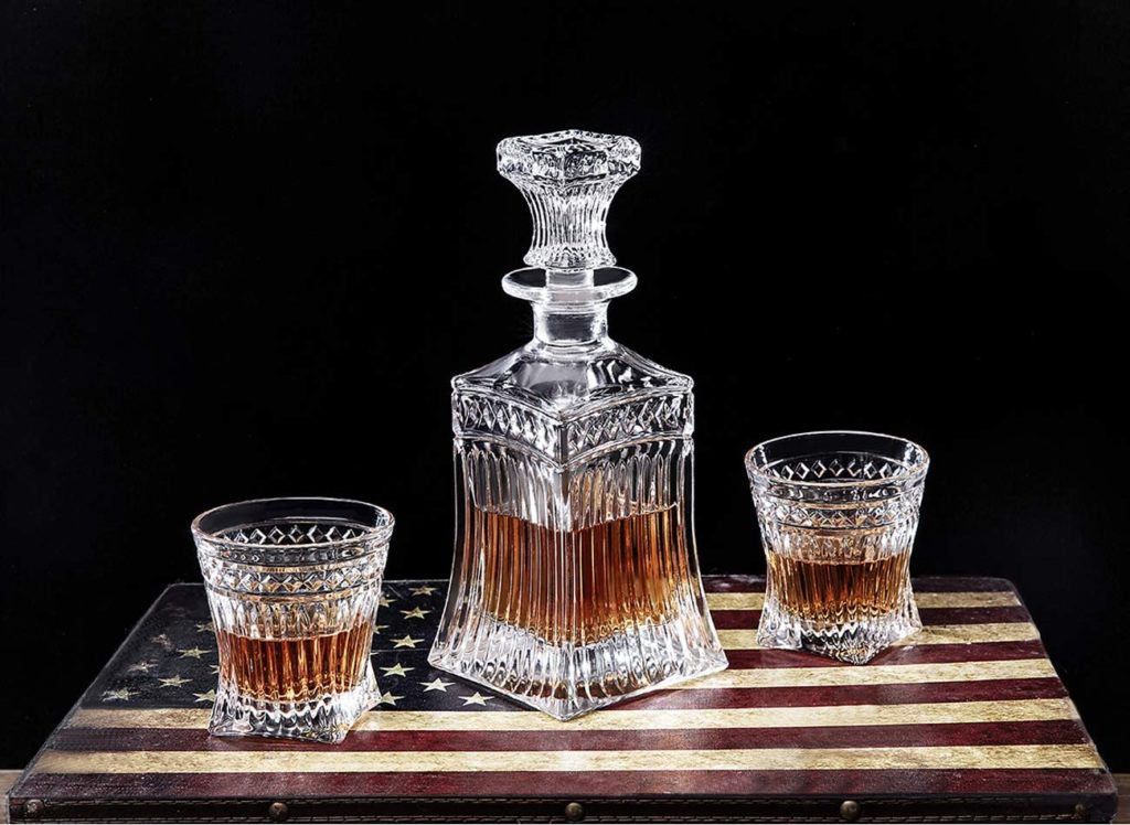 two glasses of whiskey and crystal decanter on american flag cutting board