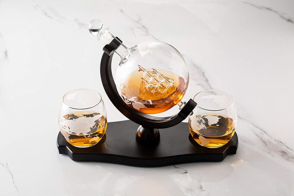 globe whiskey decanter with two matching globe whiskey glasses on black stand
