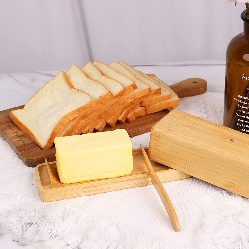 wooden butter dish next to load of sliced bread