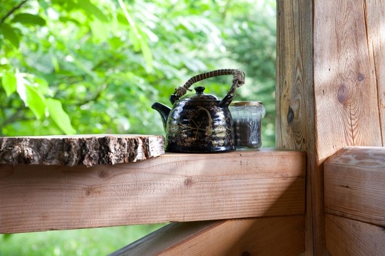 rustic black tea kettle on wooden porch outside