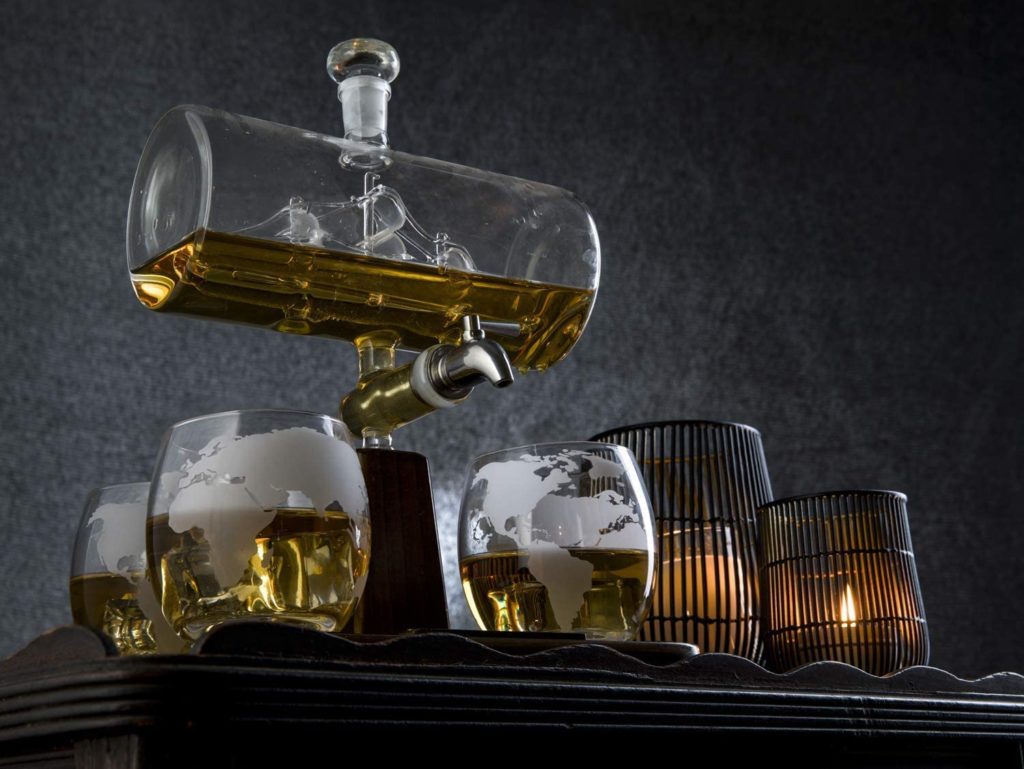 modern raised decanter pouring whiskey into globe patterned glasses