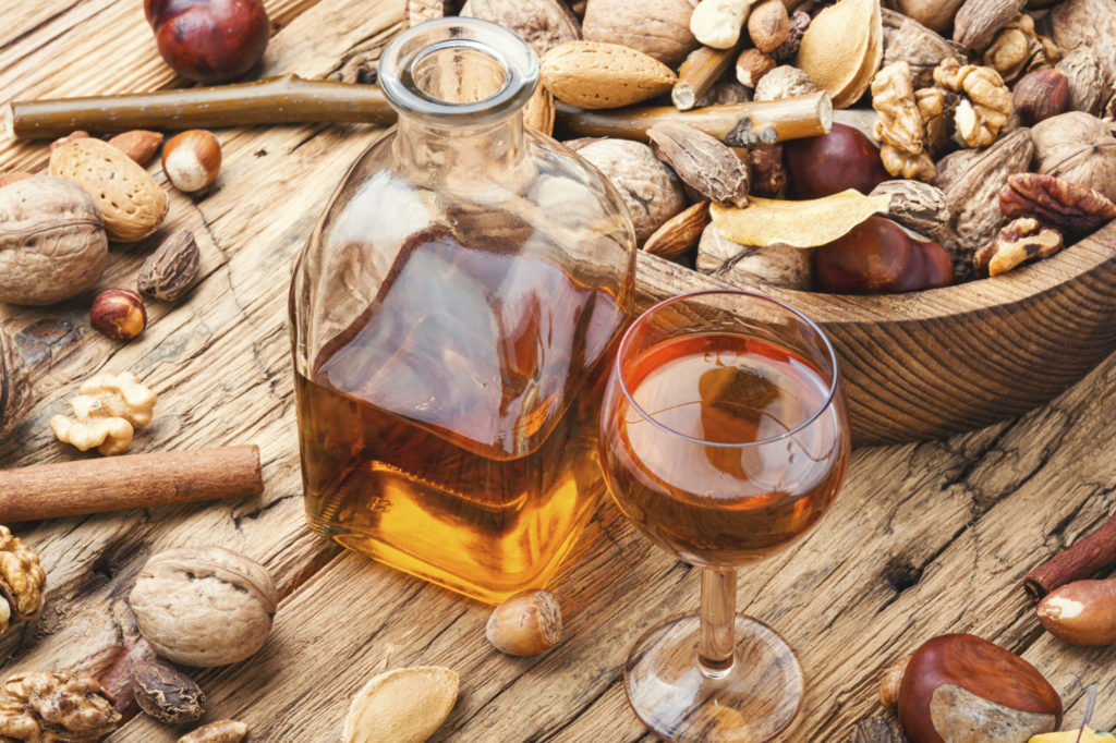 whiskey and decanter on wooden table top surrounded by nuts