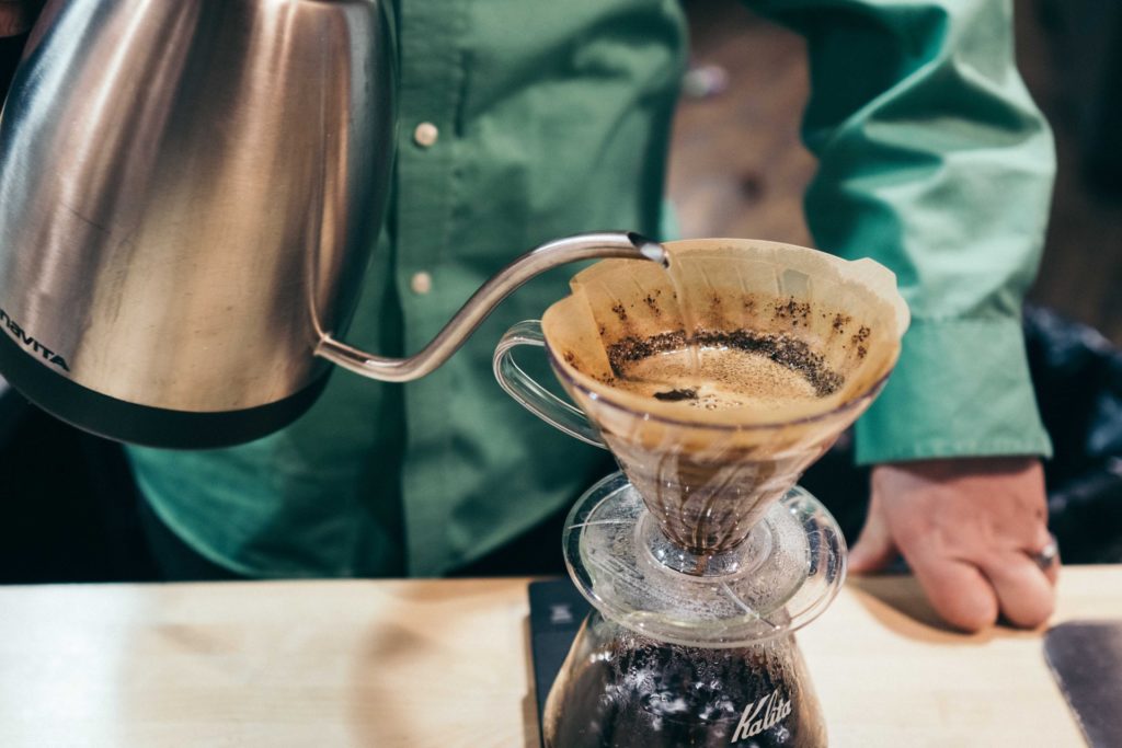 person pouring hot water in a pour over coffee decanter