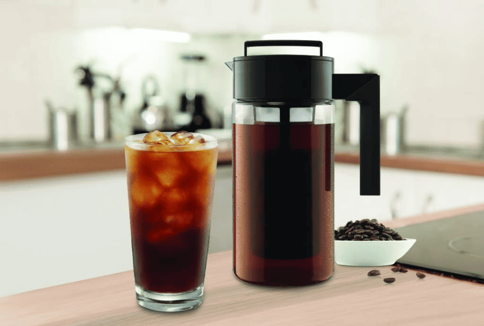 cold brew coffee pitcher on counter next to cup of coffee