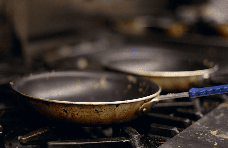 dirty in use stainless steel frying pan on stove