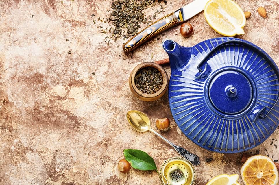 flatlay of blue ceramic tea kettle styled with tea