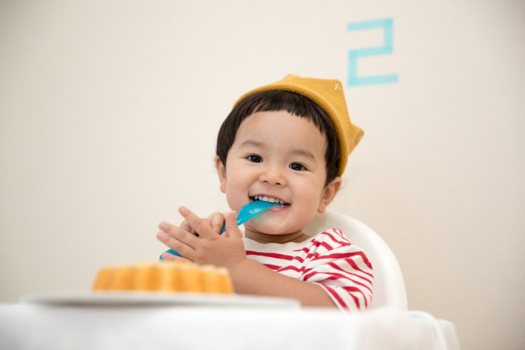 happy baby in high chair eating with spoon
