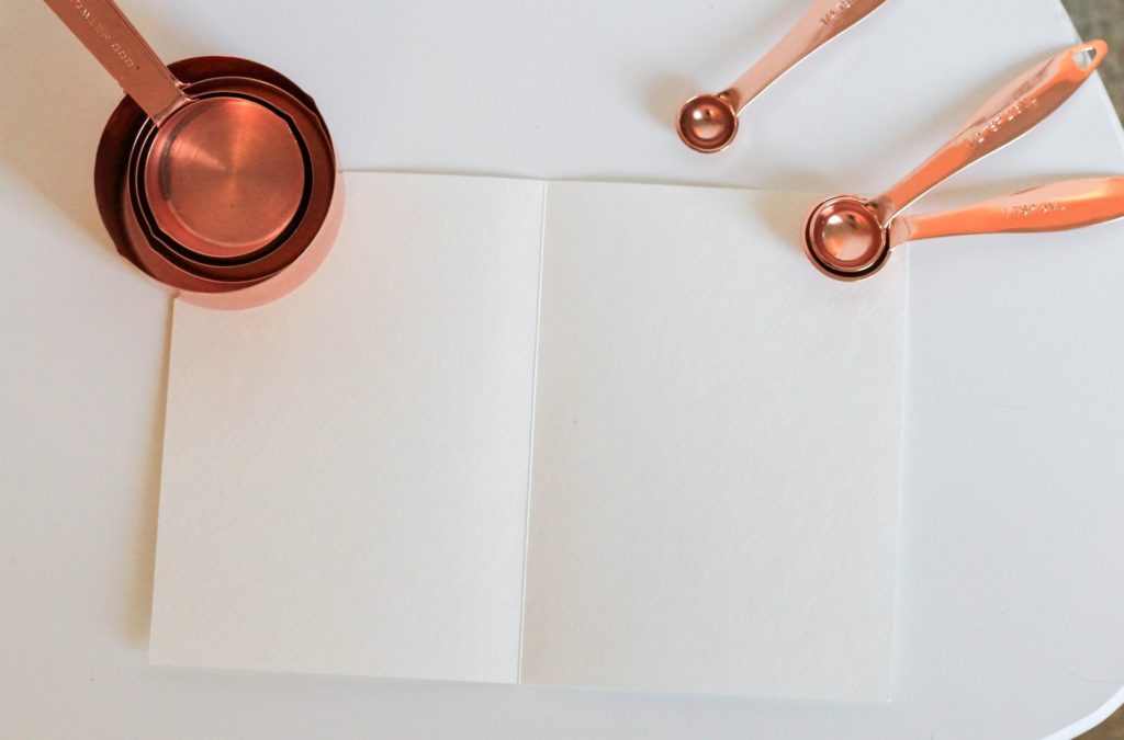 copper measuring spoons and cups on white paper