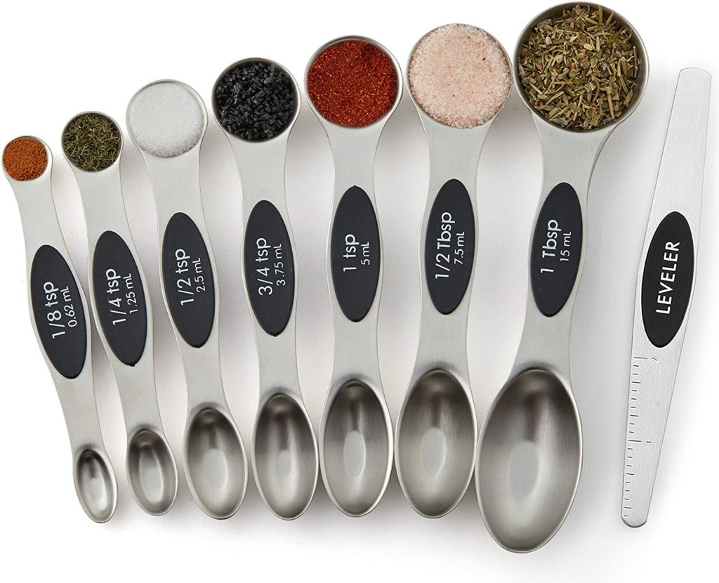set of double sided stainless steel measuing spoons with leveler filled with spices