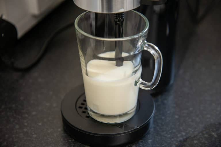 milk being frothed in glass mug