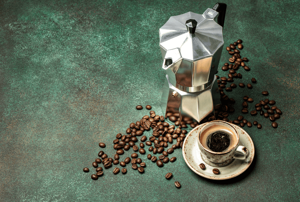 moka stovetop espresso maker styled with beans on a green table