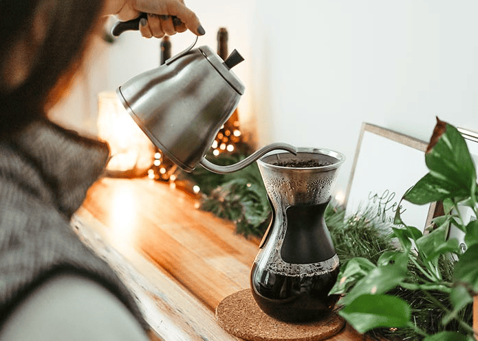 person making pourover coffee with stainless steel gooseneck kettle