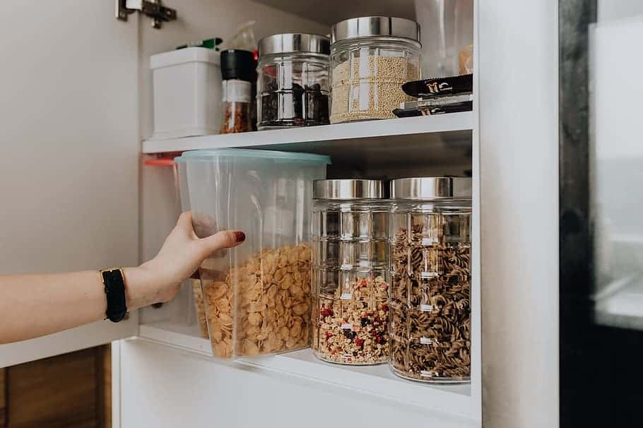 persons arm reaching into pantry full of cereal containers