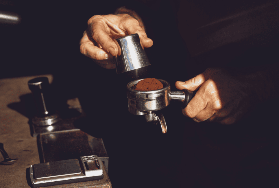 persons hand tampering espresso grinds