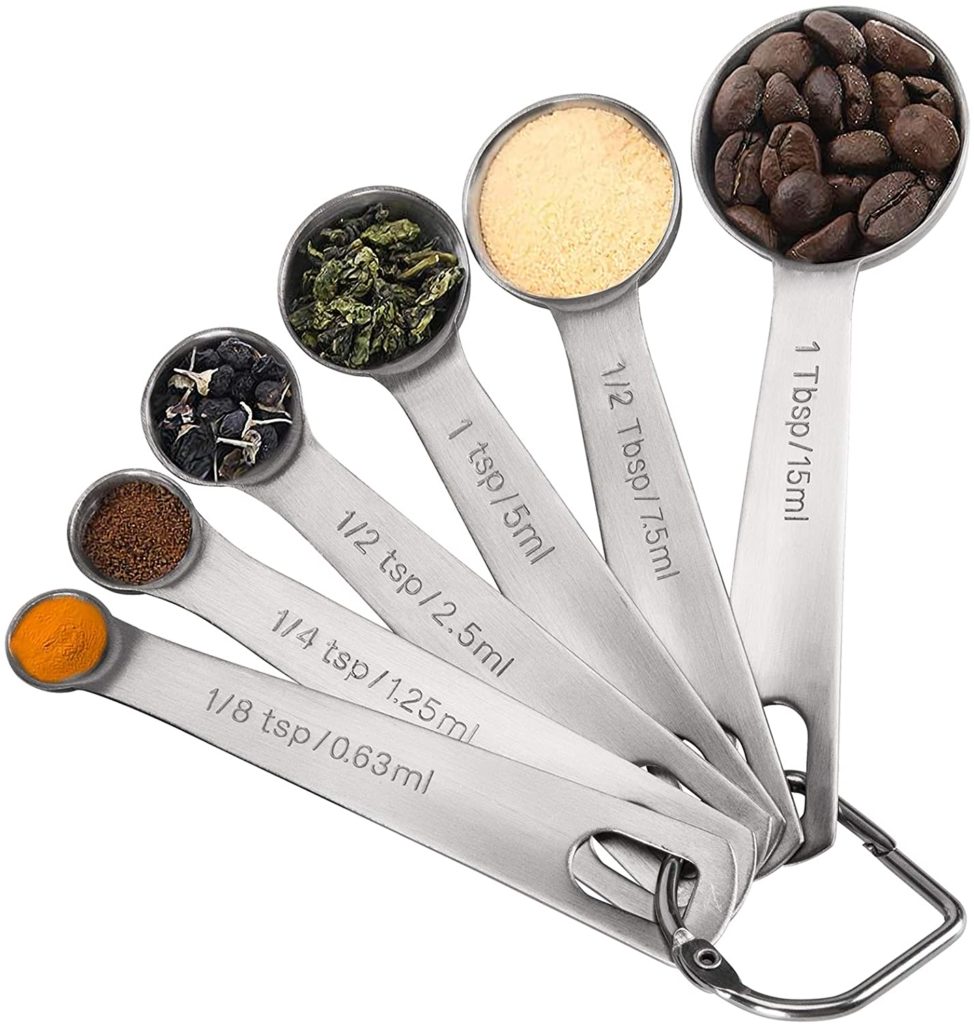 set of round stainless steel measuring spoons filled with various spices and ingredients
