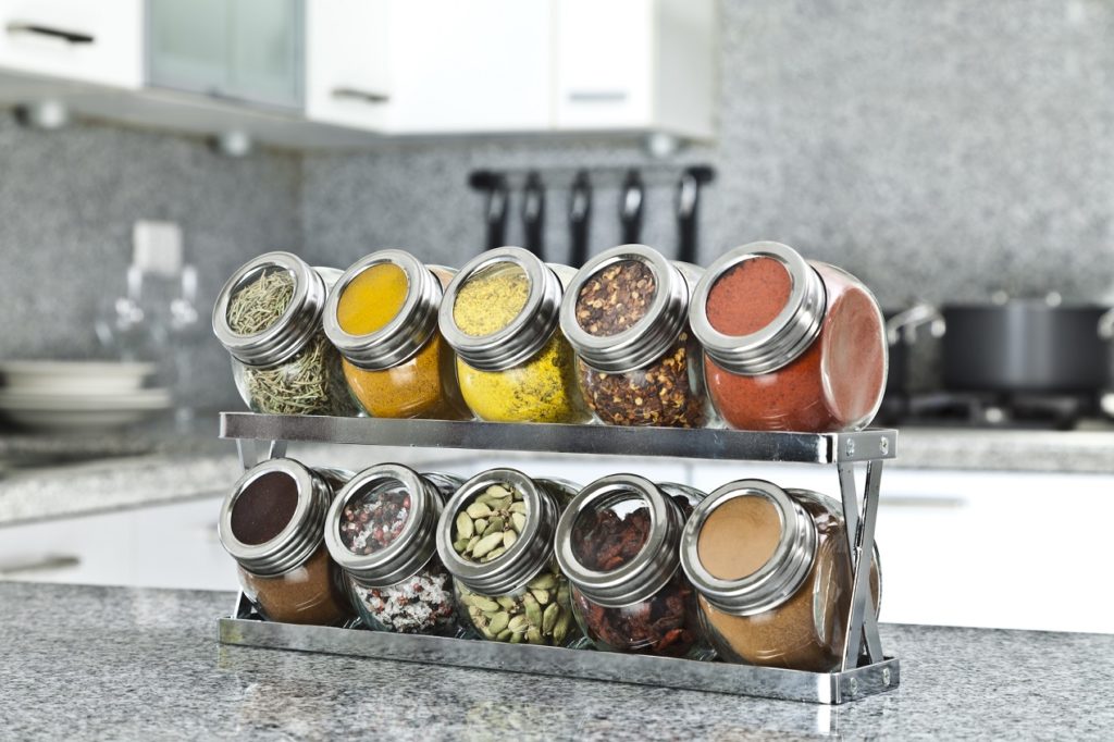 glass round spice jars neatly organized in kitchen counter spice rack