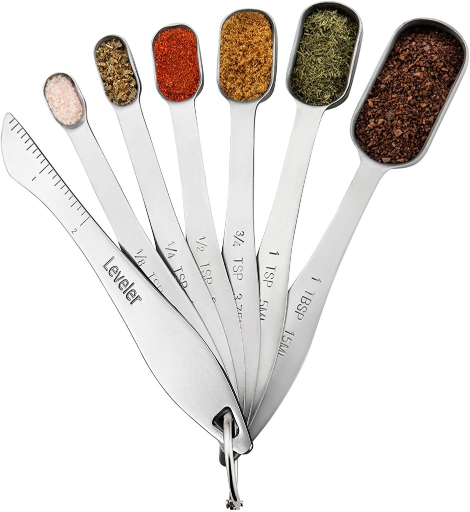set of square stainless steel measuring spoons filled with various spices and a leveler
