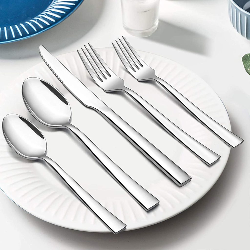two silver forks, two spoons and one knife on white plate