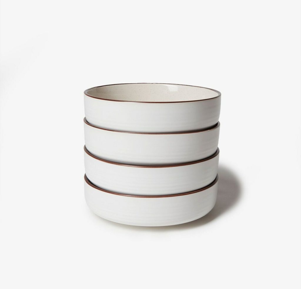 stack of four white ceramic bowls with brown rims
