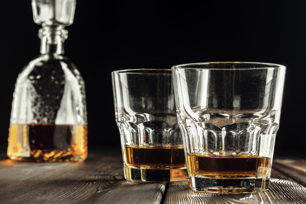 Whiskey glass and bottle on the old wooden table