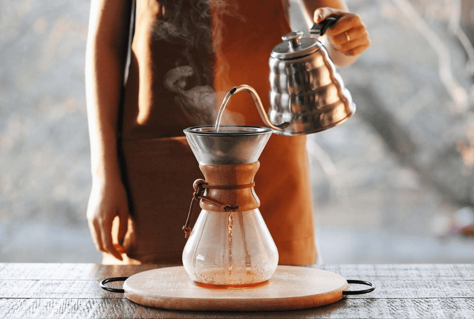 woman pouring water into pour over coffee maker
