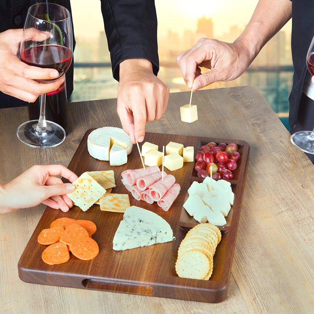 charcuterie board with peoples hands reaching for food