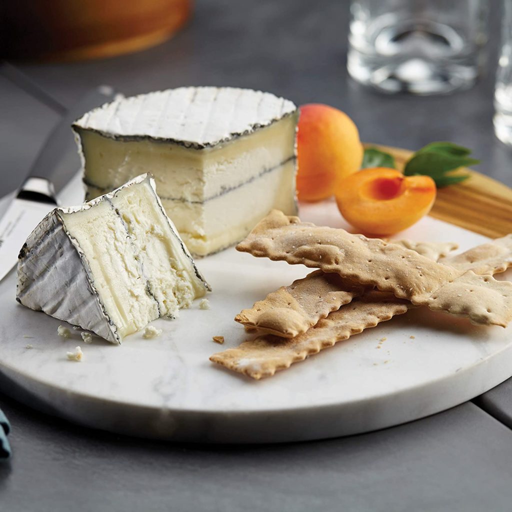 cheese and crackers on round marble cutting board
