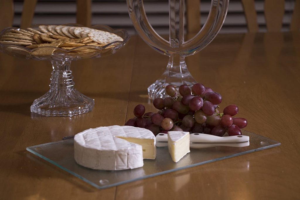 cheese and grapes on glass cutting board with fancy glass decor