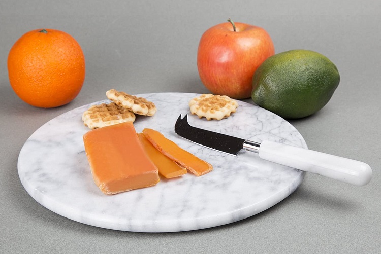 cheese and snacks on white and grey round marble cutting board