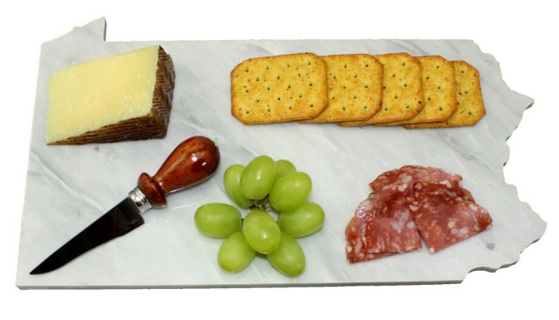 cheese and snacks on white cutting board with knife