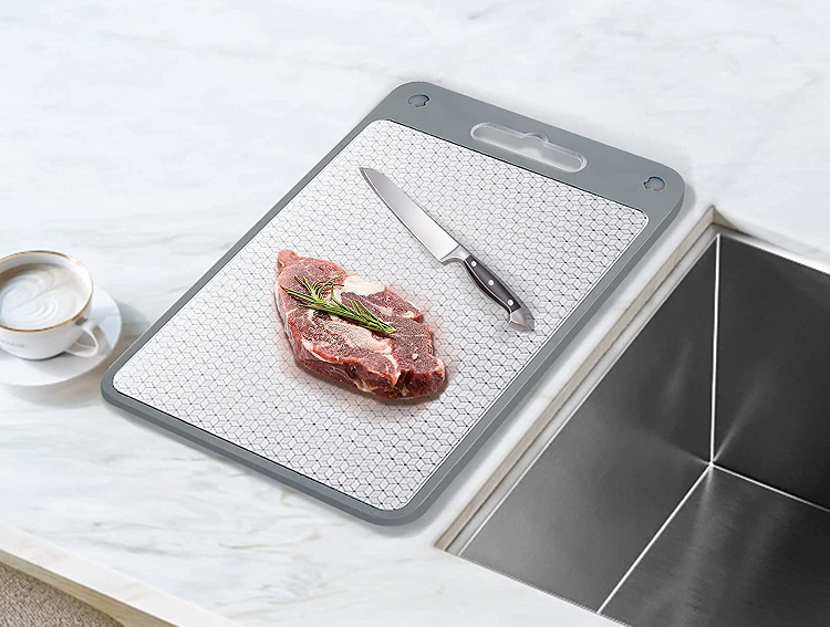 cutting board next to sink with knife and meat