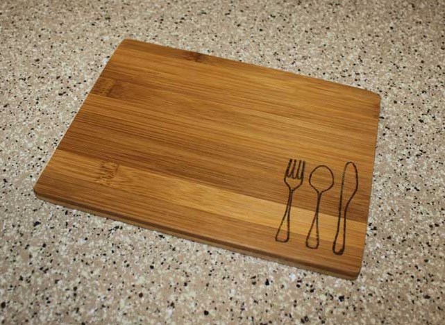 fork spoon and knife outline burnt into wooden cutting board