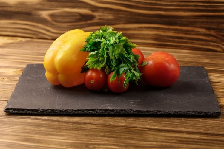 fresh produce piled neatly on raw edge black stone cutting board