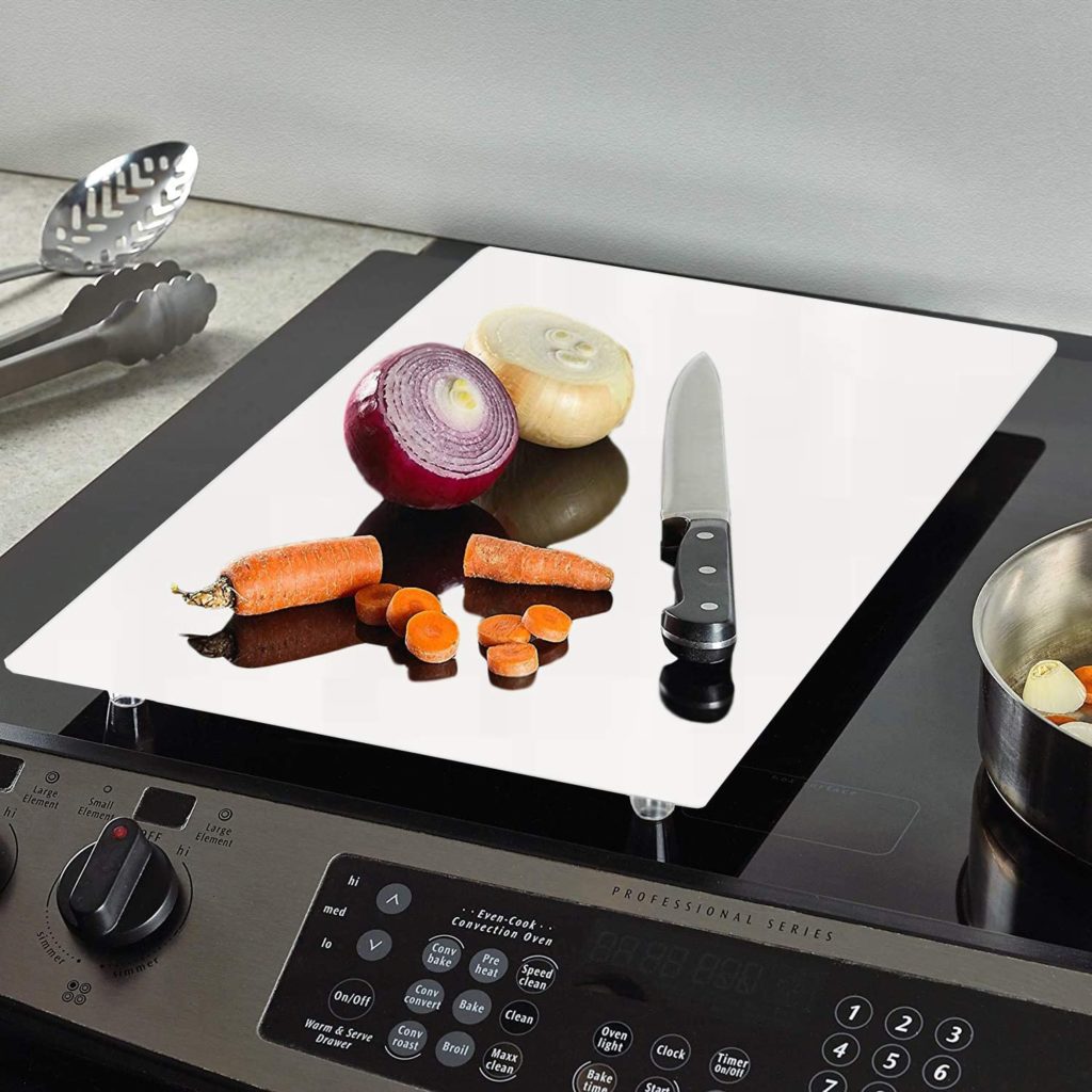 glass cutting board on a stove with produce