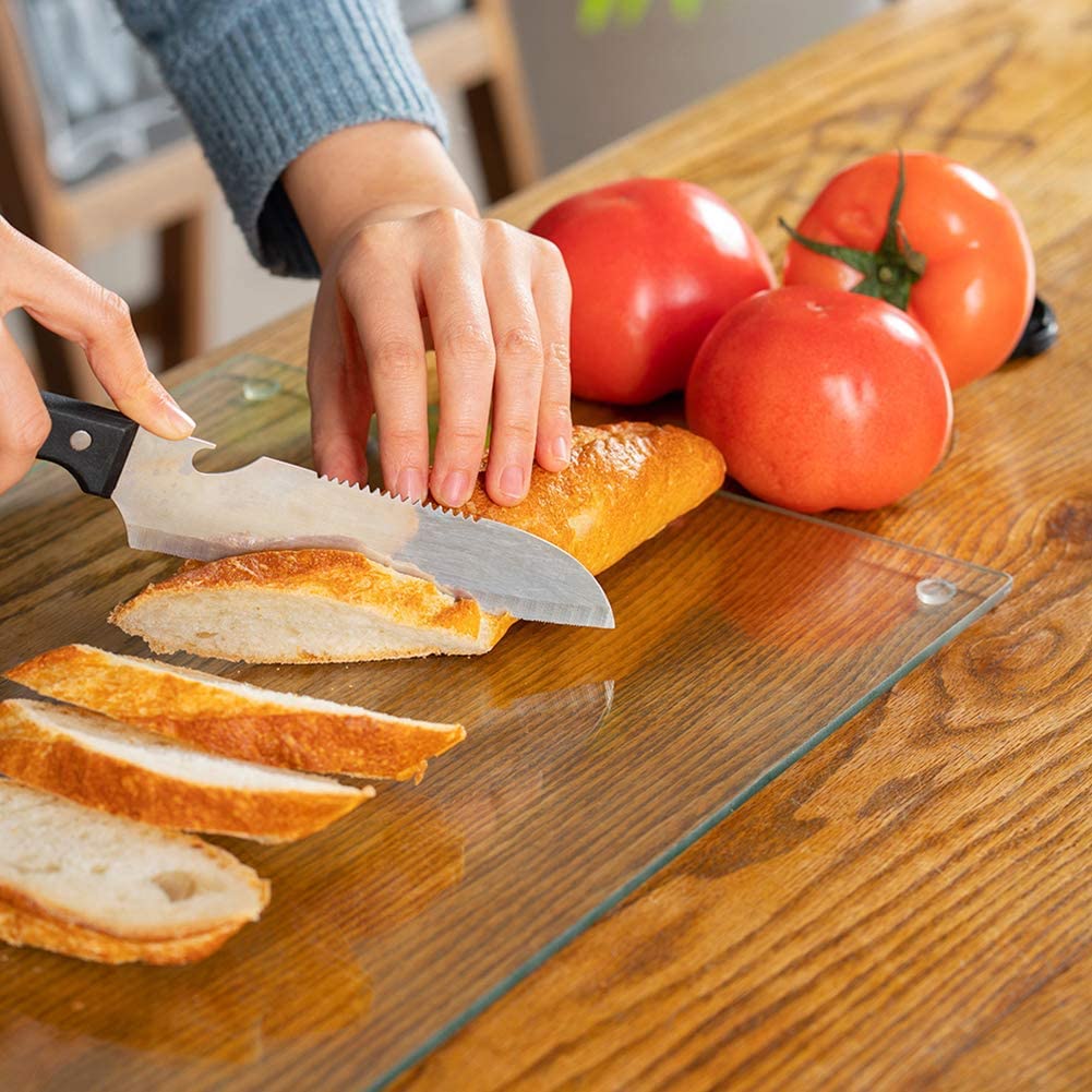 hand slicing bread on glass cutting board