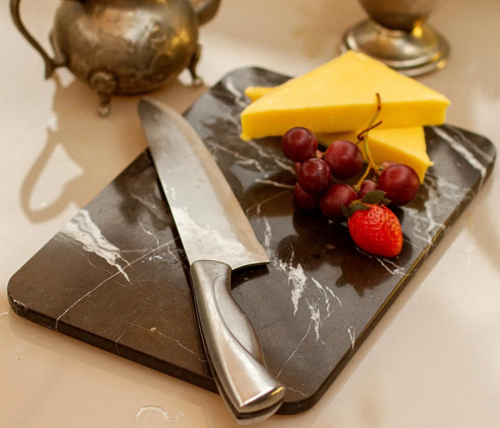 knife and cheese on black marble cutting board